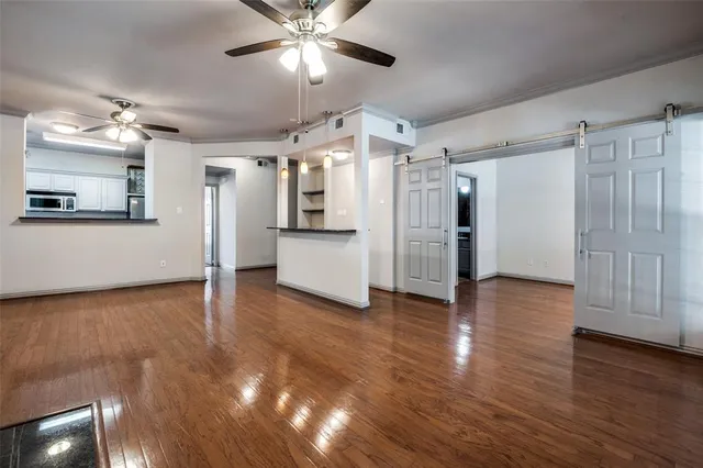 a view of a livingroom with wooden floor a ceiling fan and windows