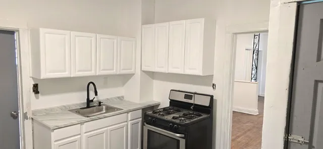 a kitchen with stainless steel appliances granite countertop white cabinets and a stove
