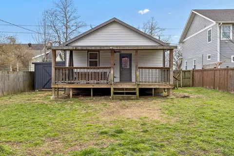 a view of yellow house with wooden fence