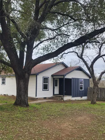 a view of a yard in front of a house with a large tree