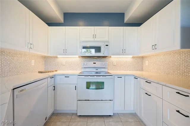 a kitchen with white cabinets and white appliances