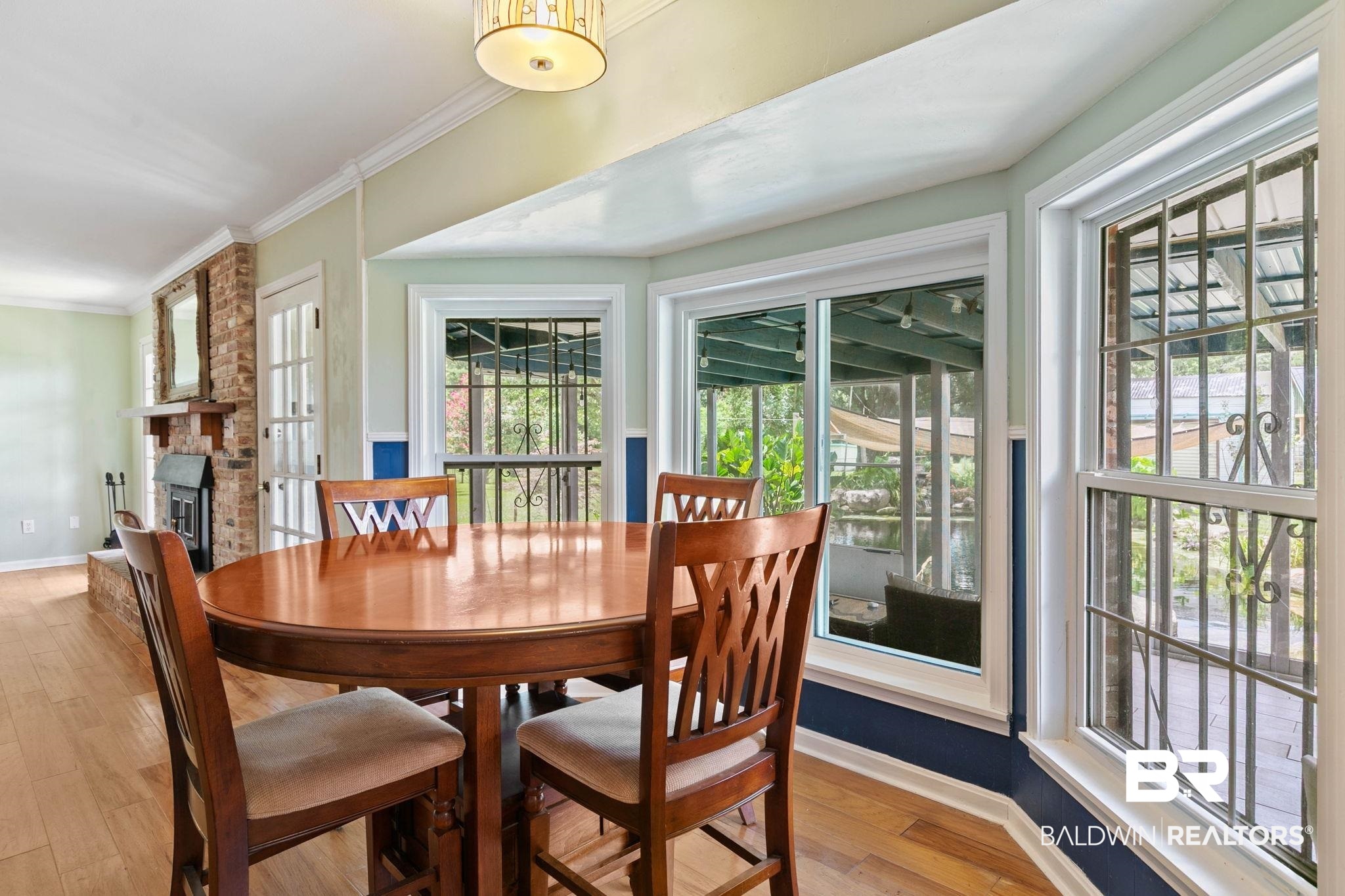 3791 Robinsonville Road Atmore, AL 36502 - Photo 17 of 55 Bay window area with wood-finish flooring, a contemporary ceiling light fixture, and a brick-faced fireplace with a black insert