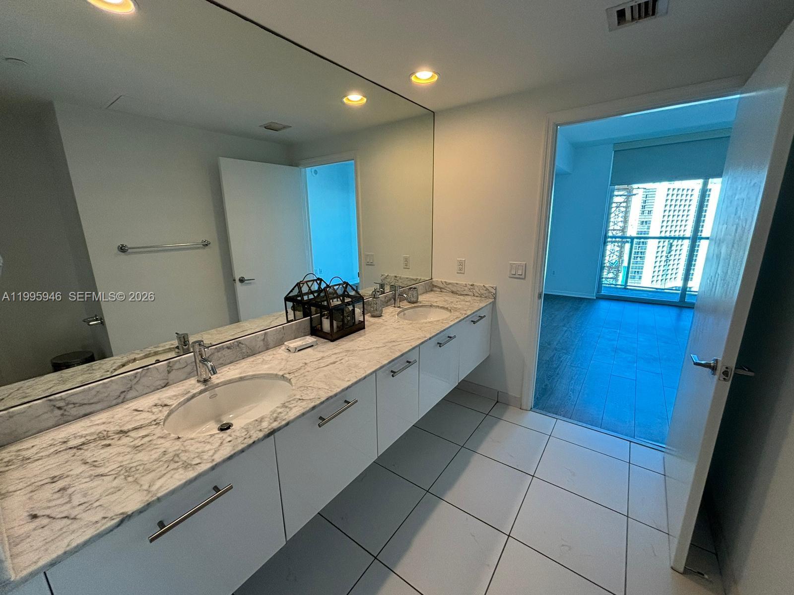 55 Southeast 6th Street, Unit 2005 Miami, FL 33131 - Photo 17 of 40 a bathroom with a granite countertop sink a mirror and a bathtub