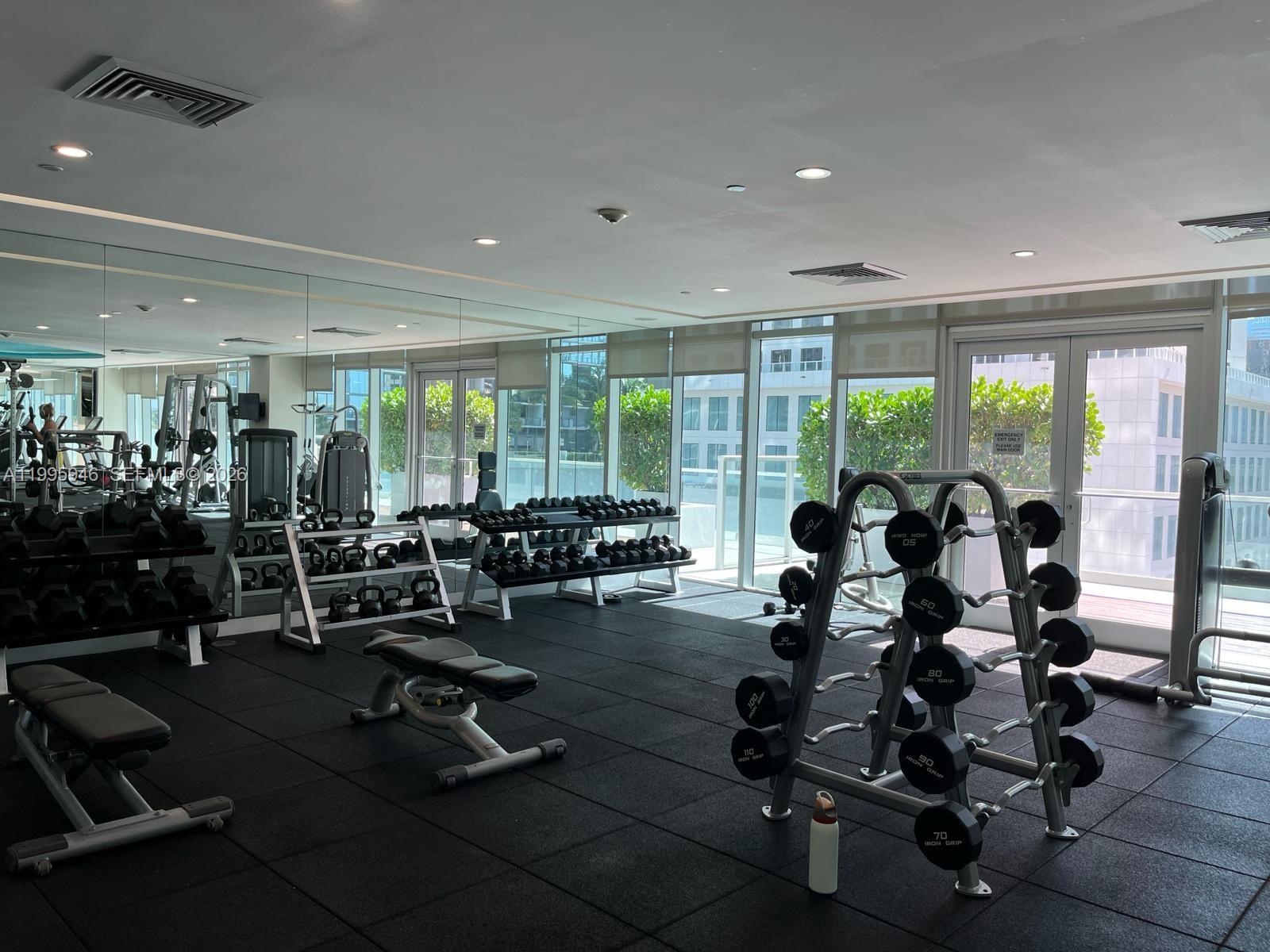 55 Southeast 6th Street, Unit 2005 Miami, FL 33131 - Photo 32 of 40 a view of a room with gym equipment and floor to ceiling window