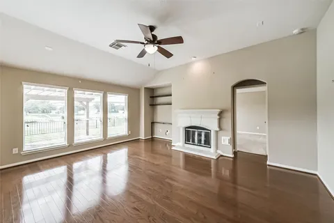a view of an empty room with a fireplace and wooden floor