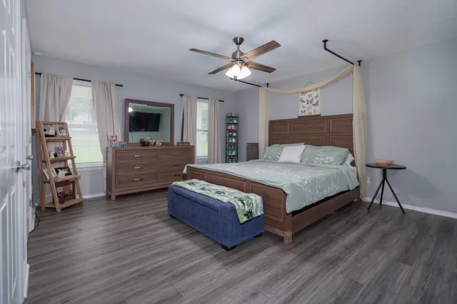 a bedroom with a large bed a flat tv screen and a dresser