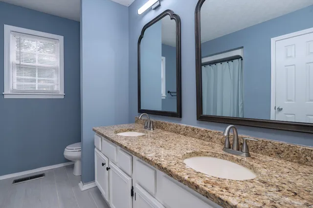 a bathroom with a granite countertop sink a toilet and a mirror