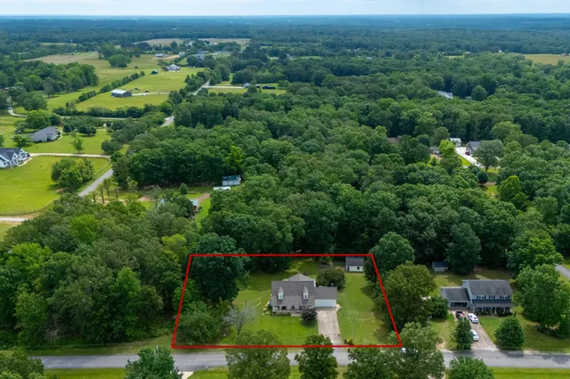 an aerial view of a houses with outdoor space and trees all around
