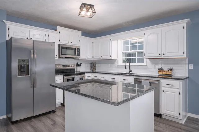 a kitchen with stainless steel appliances granite countertop a sink stove and refrigerator