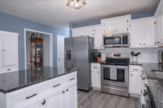 a kitchen with granite countertop white cabinets and stainless steel appliances