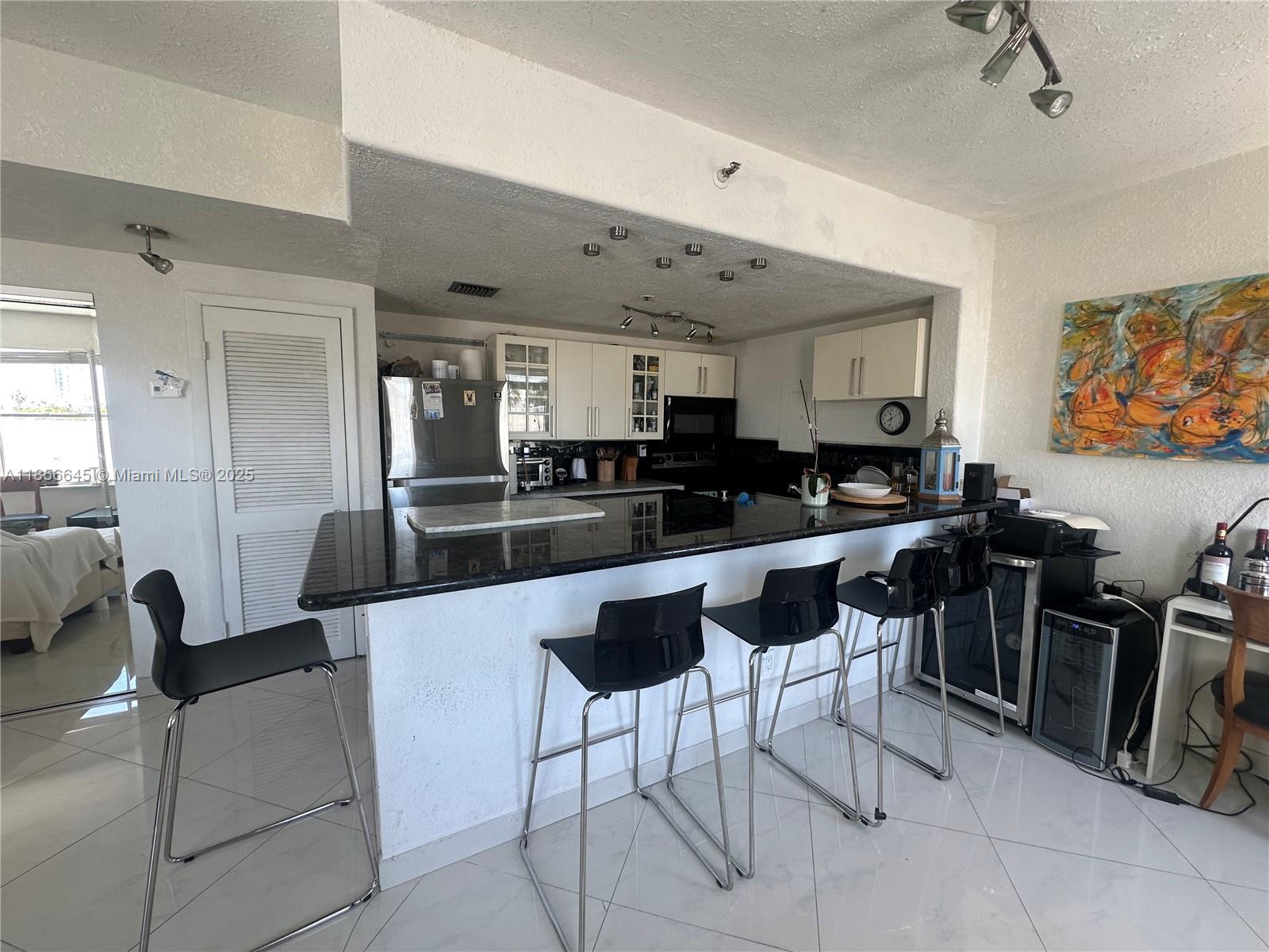 802 Euclid Avenue, Unit 305 Miami Beach, FL 33139 - Photo 2 of 13 a kitchen with stainless steel appliances kitchen island granite countertop a stove a sink a dining table and chairs