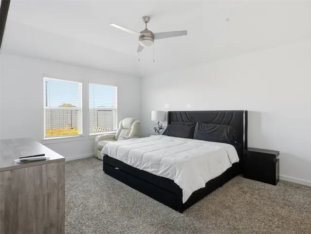 a bedroom with a bed lamp and a large window