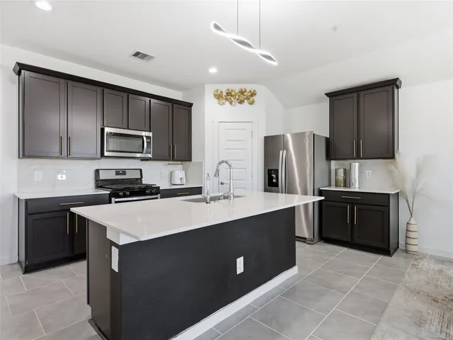 a kitchen with stainless steel appliances a sink stove refrigerator and cabinets