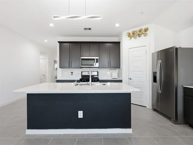a kitchen with kitchen island stainless steel appliances a sink a refrigerator and a stove