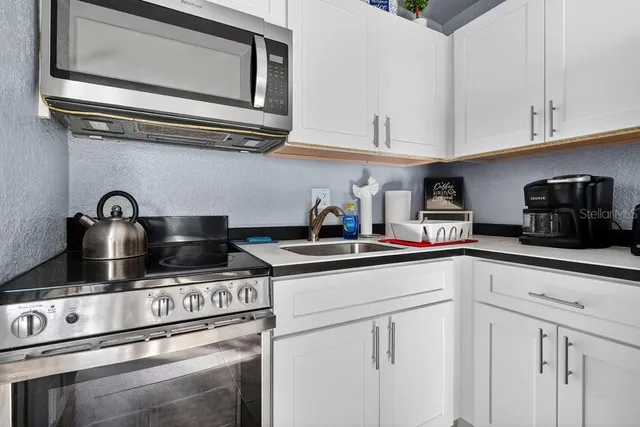 a kitchen with white cabinets a sink and appliances