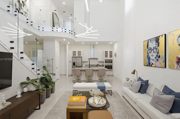 a living room with furniture kitchen view and a chandelier