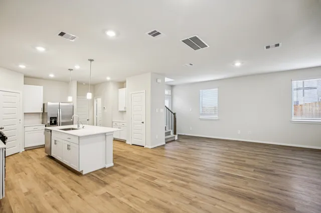 a living room with stainless steel appliances kitchen island hardwood floor sink and stove
