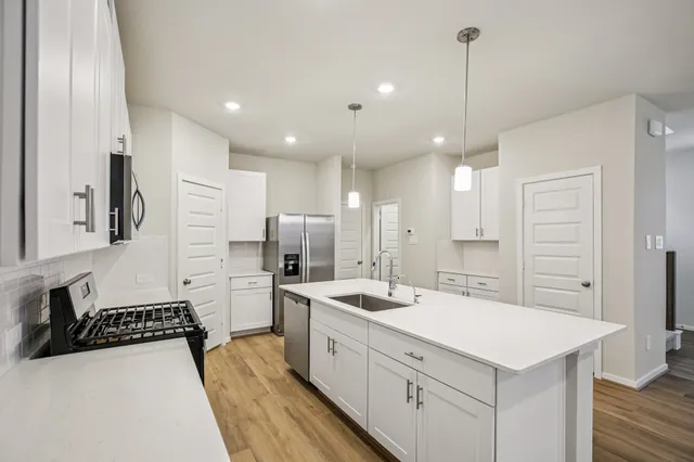 a kitchen with stainless steel appliances a sink a stove a refrigerator and cabinets