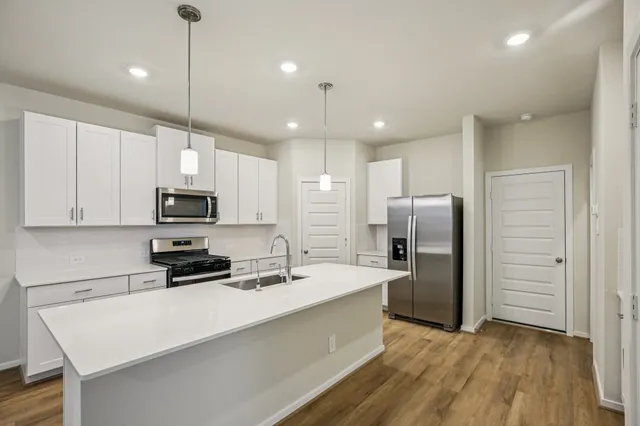 a kitchen with stainless steel appliances a refrigerator sink a stove a center island and cabinets