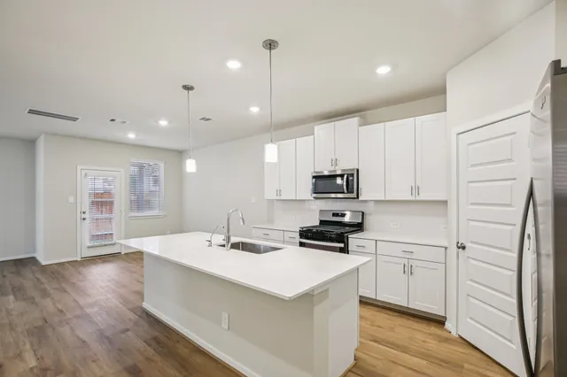a kitchen with stainless steel appliances white cabinets a sink a stove a refrigerator and cabinets