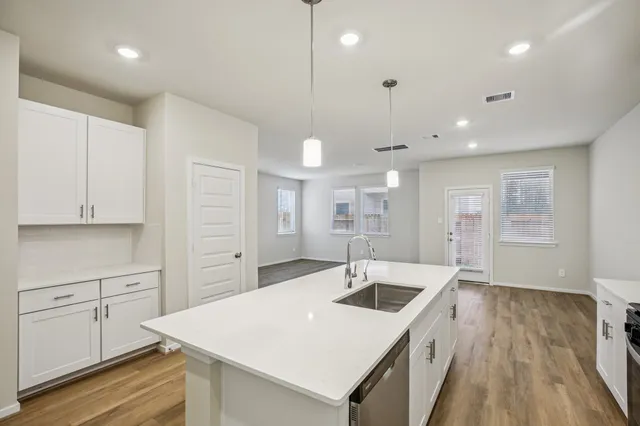 a kitchen with a sink a stove a refrigerator and white cabinets with wooden floor