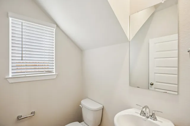 a bathroom with a toilet a sink a mirror and a window