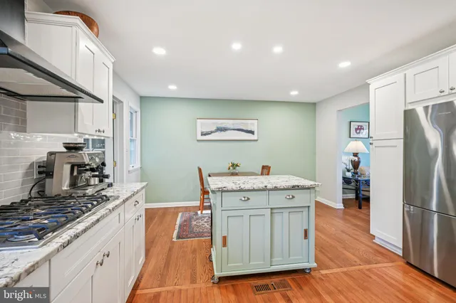 a kitchen with stainless steel appliances granite countertop a refrigerator a stove and a wooden floors