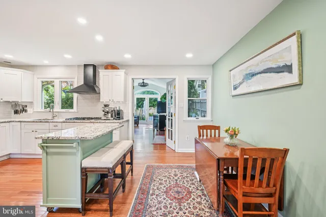 a dining hall with stainless steel appliances granite countertop a stove a sink a dining table and chairs with wooden floor