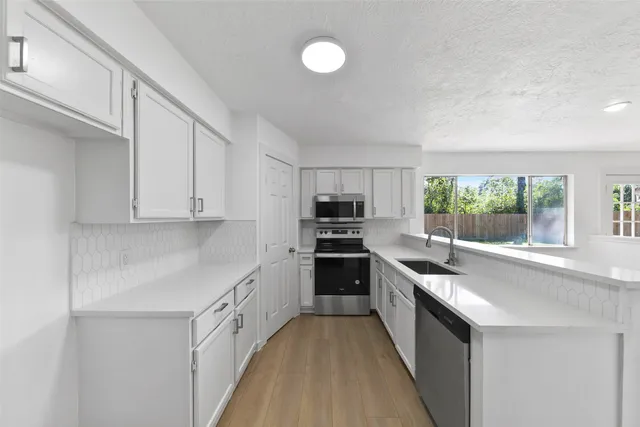 a kitchen with stainless steel appliances granite countertop lots of counter space and wooden floors