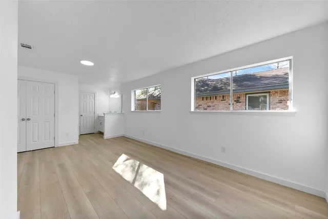 a view of an empty room with wooden floor and a window