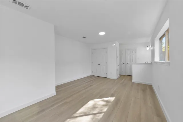 a view of an empty room with wooden floor and a window