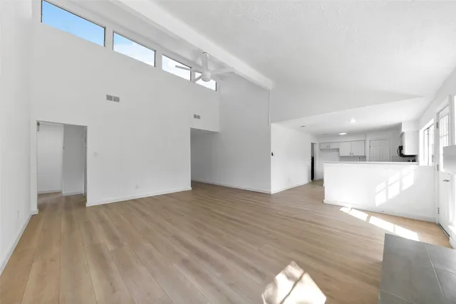 a view of a big room with wooden floor and windows