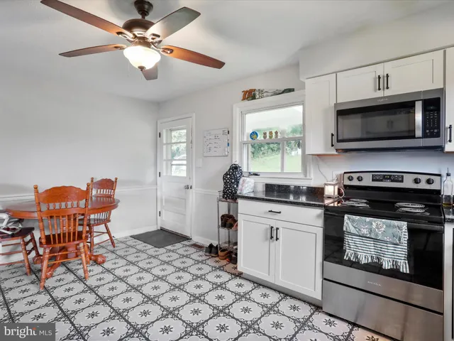 a kitchen with stainless steel appliances granite countertop a stove top oven a sink a dining table and chairs