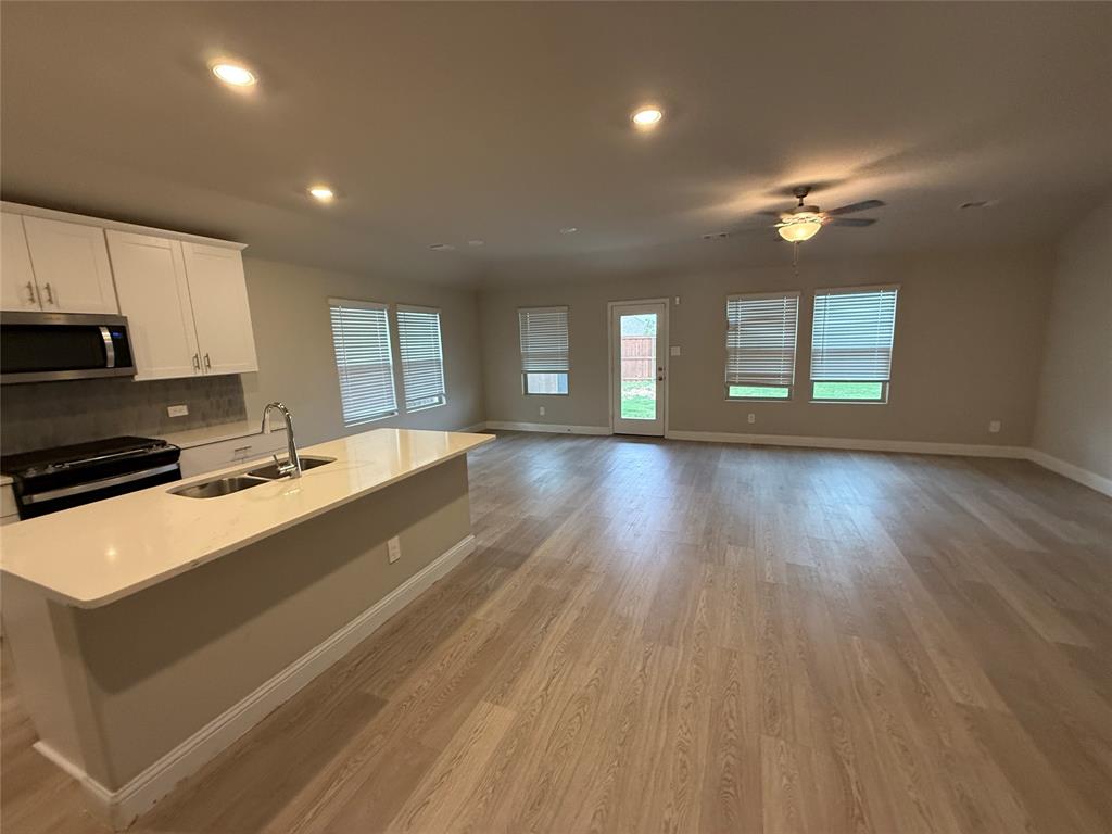 702 Williams Way Lowry Crossing, TX 75069 - Photo 2 of 22 a large hall with stainless steel appliances granite countertop a stove a sink dishwasher and a oven with wooden floor