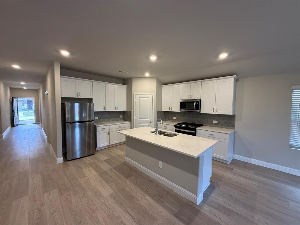 702 Williams Way Lowry Crossing, TX 75069 - Photo 6 of 22 a large kitchen with stainless steel appliances kitchen island a large counter top and a stove top oven