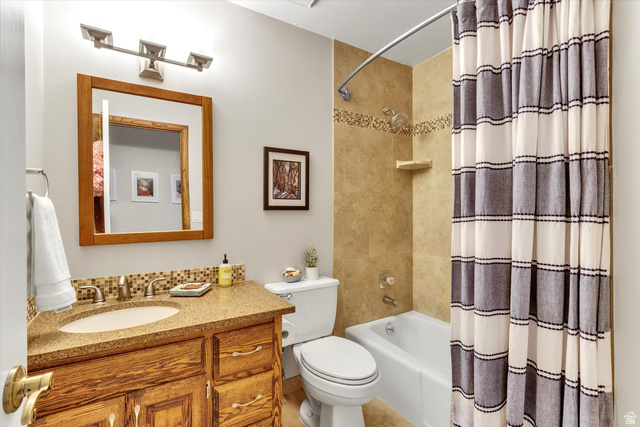 2863 Fallentine Road Sandy, UT 84093 - Photo 20 of 48 Bathroom featuring a wood-finish vanity with an integrated sink, a speckled countertop, and a tiled backsplash