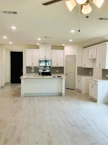 a large kitchen with a stove top oven a sink a counter space and cabinets