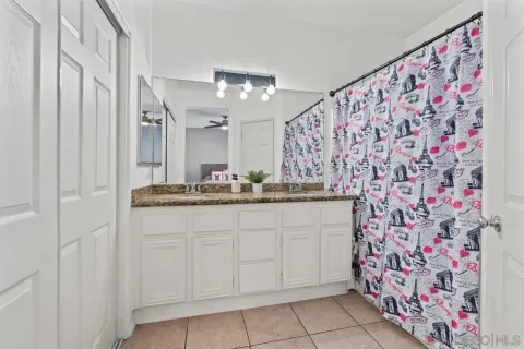 a bathroom with a granite countertop sink a mirror and shower curtain
