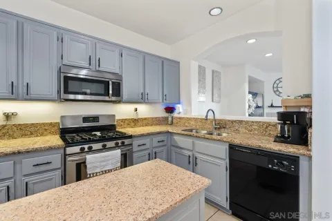 a kitchen with stainless steel appliances granite countertop a stove a sink and a microwave