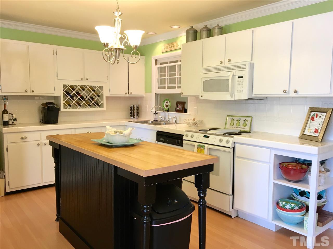 403 Kevin Circle Raleigh, NC 27609 - Photo 7 of 25 a kitchen with a sink a stove a refrigerator and white cabinets