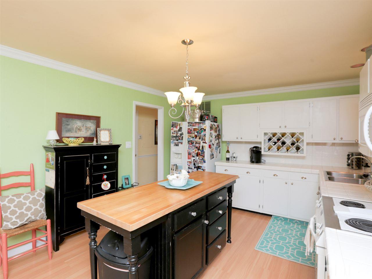 403 Kevin Circle Raleigh, NC 27609 - Photo 9 of 25 a kitchen with a stove a sink dishwasher and a dining table with wooden floor