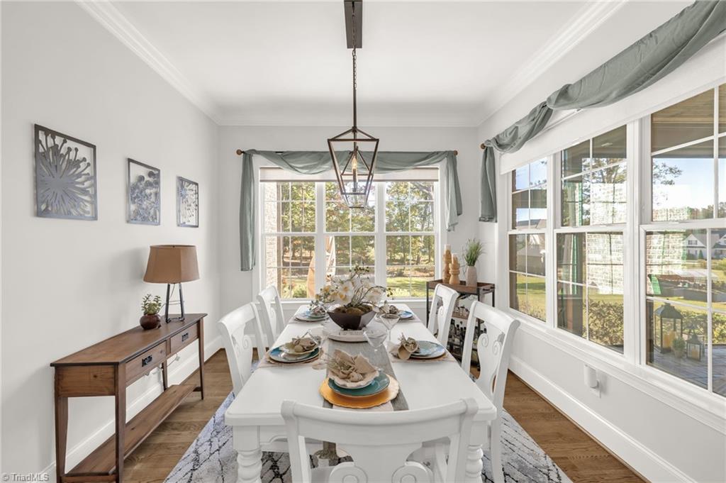 4262 Bridgehead Road Kernersville, NC 27284 - Photo 16 of 50 Dining Room – Inviting dining area framed by oversized windows, featuring crown molding and a modern chandelier for intimate meals or family gatherings.
