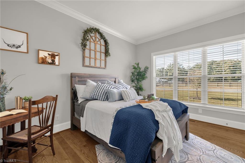 4262 Bridgehead Road Kernersville, NC 27284 - Photo 21 of 50 Guest Bedroom – Welcoming main-level guest suite featuring hardwood floors, crown molding, and a bright window overlooking the front lawn.