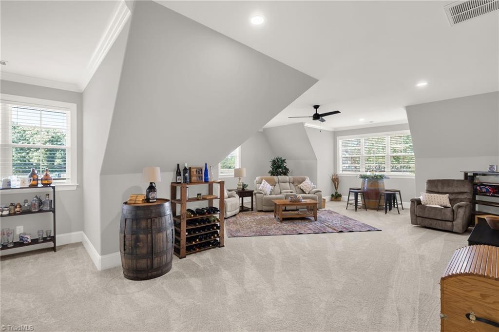 4262 Bridgehead Road Kernersville, NC 27284 - Photo 32 of 50 Expansive upstairs bonus room filled with natural light, featuring angled ceilings, recessed lighting, and flexible space ideal for relaxing, gaming, or entertaining.
