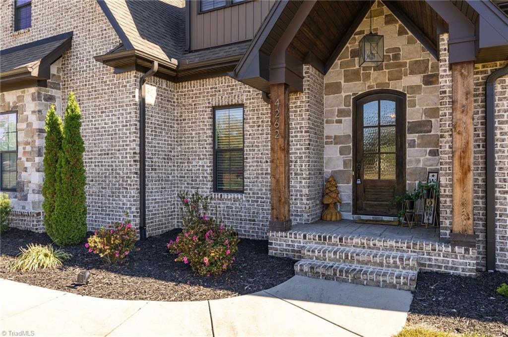 4262 Bridgehead Road Kernersville, NC 27284 - Photo 4 of 50 Front Entry – Inviting covered entry with wood accents, textured glass door, and stylish stonework that sets a warm, welcoming tone.