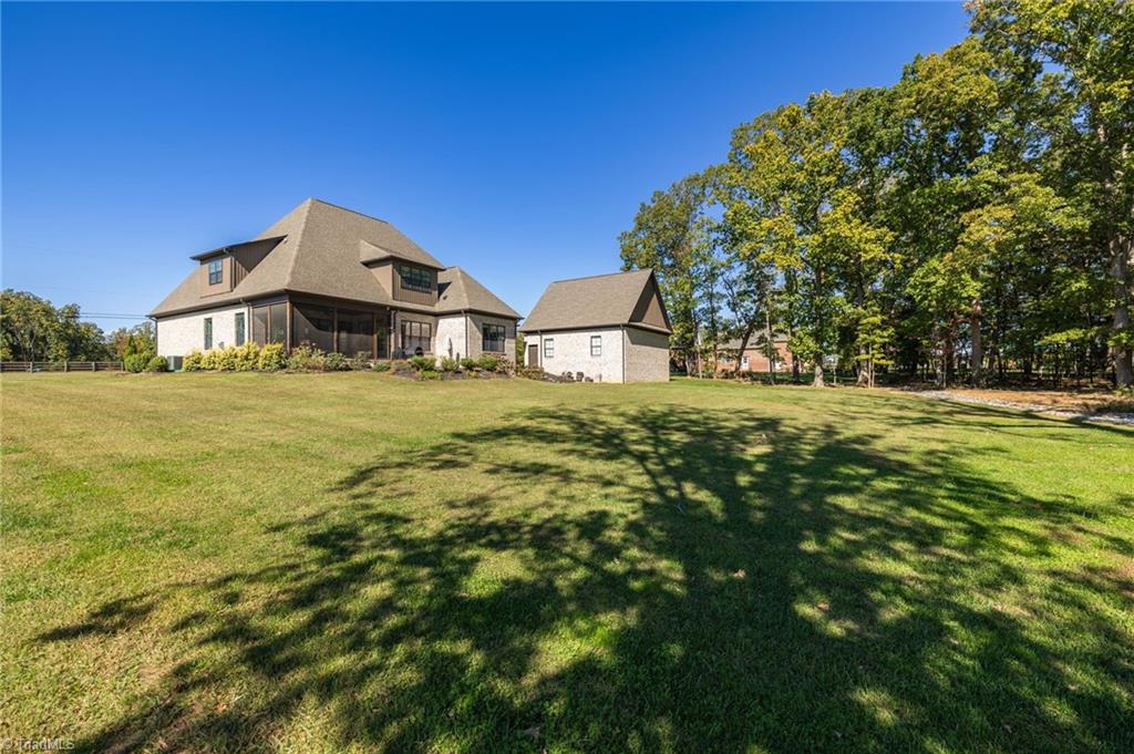 4262 Bridgehead Road Kernersville, NC 27284 - Photo 41 of 50 Rear Exterior – Stunning full view of the home’s brick façade, screened porch, and detached two-car garage showcasing thoughtful design and craftsmanship.