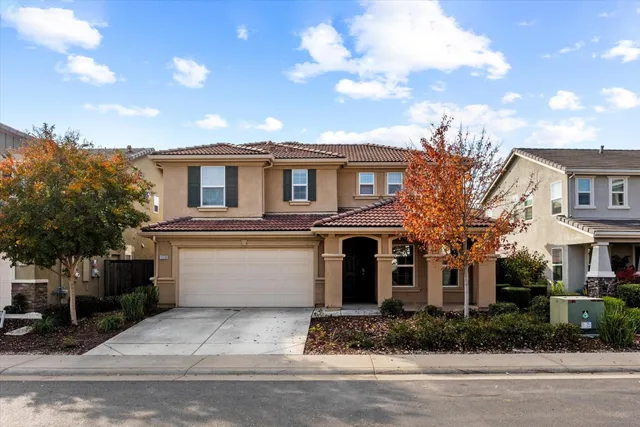 a view of a white house with a fountain and a tree