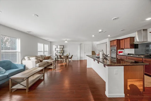 a living room with furniture kitchen view and a wooden floor