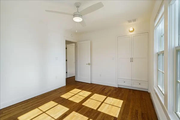 a view of an empty room with a window and wooden floor