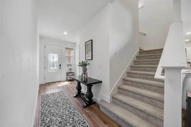 a kitchen with a refrigerator a stove top oven a sink dishwasher and white cabinets with wooden floor